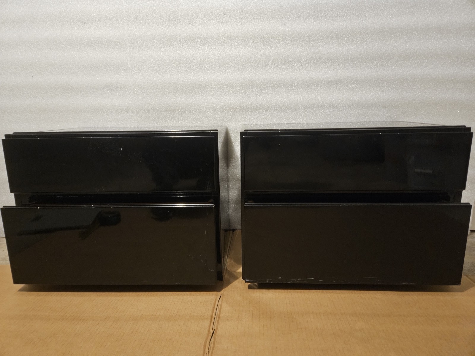 Two modern, functional two-drawer nightstands with a high-gloss black finish.